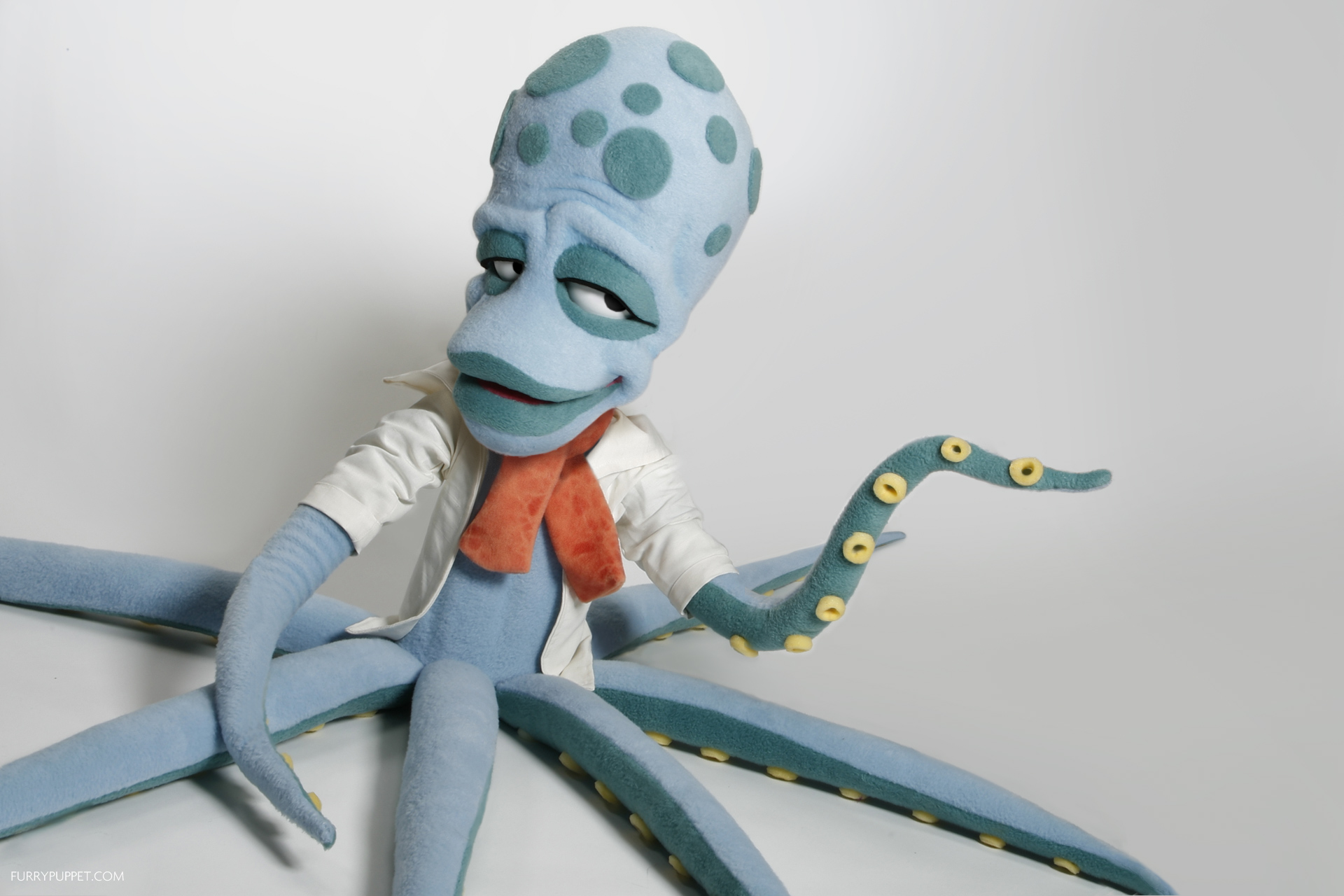 Blue octopus puppet in a white jacket and orange scarf built by Furry Puppet Studio